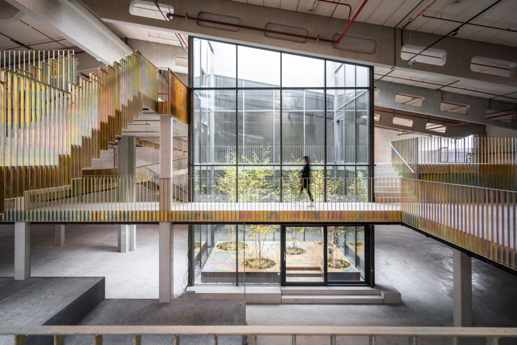 Modernisiertes Atrium im Handelszentrum 16, Bergheim bei Salzburg, mit verglastem Innenhof, begrünten Flächen und markanten, schimmernden Stahlgeländern.